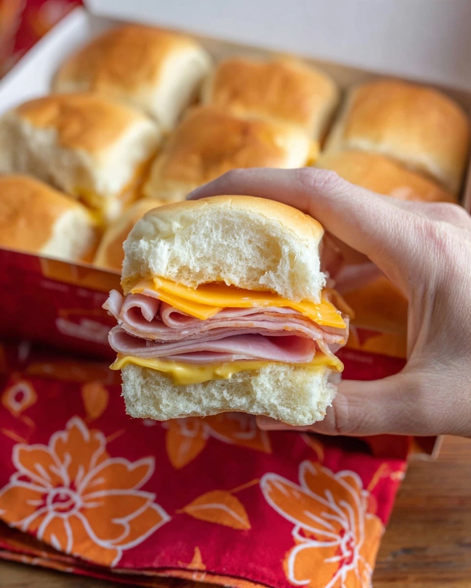The image shows a pyramid stack of six small sandwiches made with soft, light brown slider buns. Each sandwich has three main layers inside: a base layer of yellow mustard spread on the bottom bun, a middle layer of thinly folded pink ham slices, and a top layer of orange cheddar cheese with a couple of light green pickle slices visible. The buns look soft and fluffy with a slightly shiny finish on top. The sandwiches sit on a white plate placed on a white marbled surface. Photo taken with an iphone --ar 4:5 --v 7