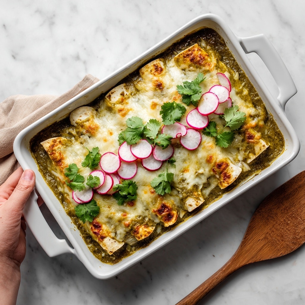 On a white plate, a layered dish is served with the bottom layer being soft white rice, topped with a yellowish shredded chicken mixed with a light green salsa sauce spread unevenly over it. Garnishing the top center are two pale green avocado slices and two thin, circular slices of radish with bright pink edges. Small green cilantro leaves are scattered on top, adding freshness, while yellow mustard seeds are visible in the salsa. A white bowl with bright red radishes sliced in half sits in the background on a striped cloth, and part of a white casserole dish with more of the green salsa chicken mixture is slightly visible on a white marbled surface photo taken with an iphone --ar 4:5 --v 7