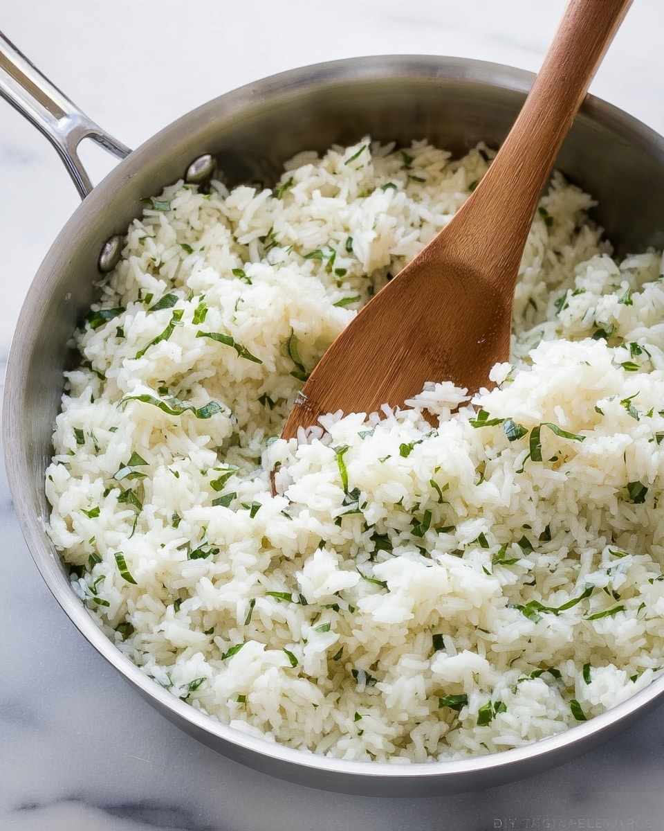 The image shows a close-up of a metal pan filled with white cooked rice mixed with small pieces of green herbs, creating a speckled green-and-white texture throughout the grains. A wooden spoon is placed vertically, partially immersed in the rice, with the handle extending out of the pan. The rice has a fluffy look and slight clumps, with a soft and light texture. The pan is set on a white marbled surface that adds a clean, bright background to the scene. photo taken with an iphone --ar 4:5 --v 7