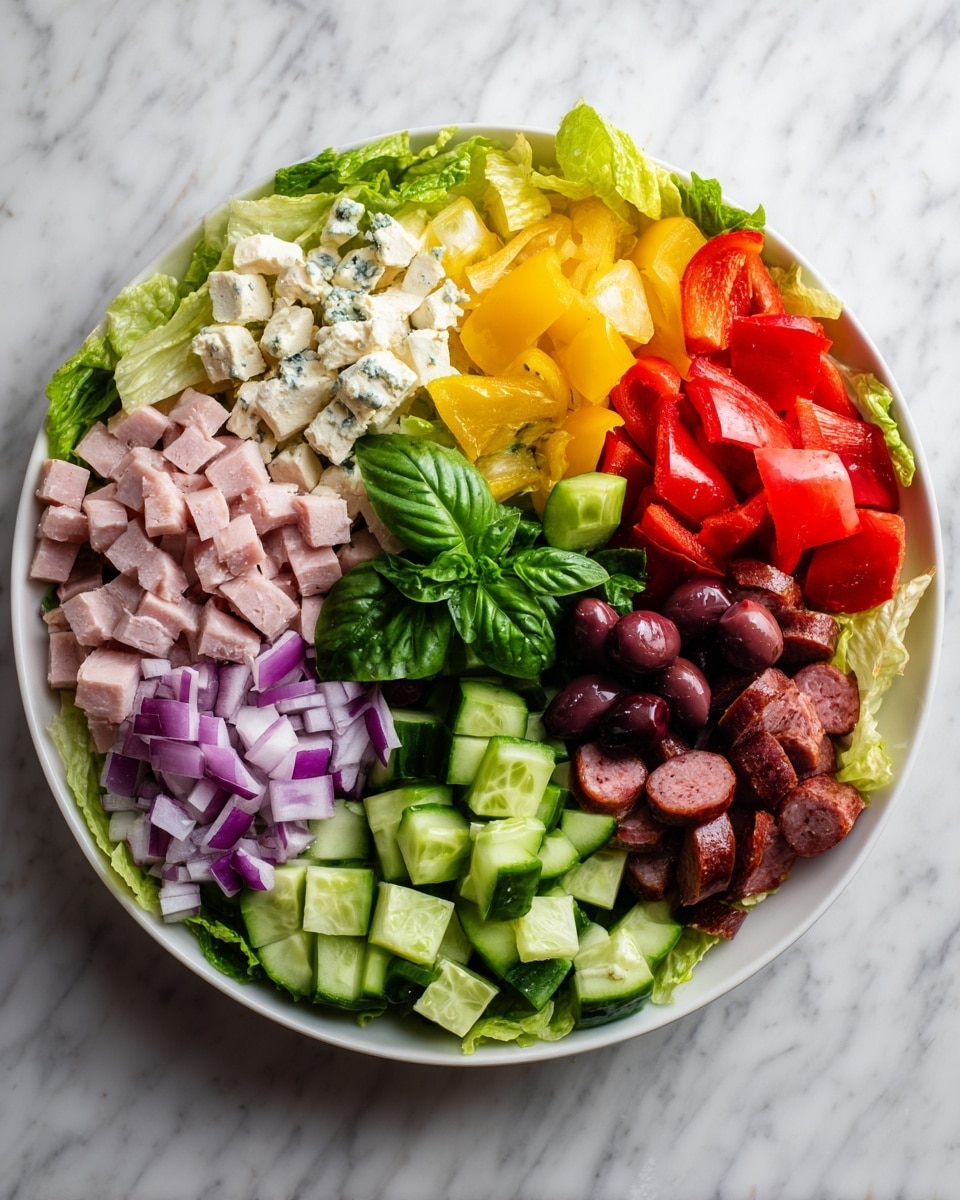 A round white plate filled with a colorful layered salad on a white marbled surface. The base layer is made of green lettuce leaves that cover the plate. On top, there are chopped purple onions on the bottom left, light pink chunks of ham or meat below the onions, and fresh cucumber cubes on the bottom right. Above the cucumbers are roasted red bell peppers, and above the onions on the left, there are chunks of white cheese with blue veins. In the center are dark purple olives, surrounded by halved cherry tomatoes and slices of dark red sausage. A small bunch of fresh green basil leaves sits in the middle. The textures vary from crispy lettuce, soft cheese, juicy tomatoes, to firm cucumber and meat. Photo taken with an iphone --ar 4:5 --v 7