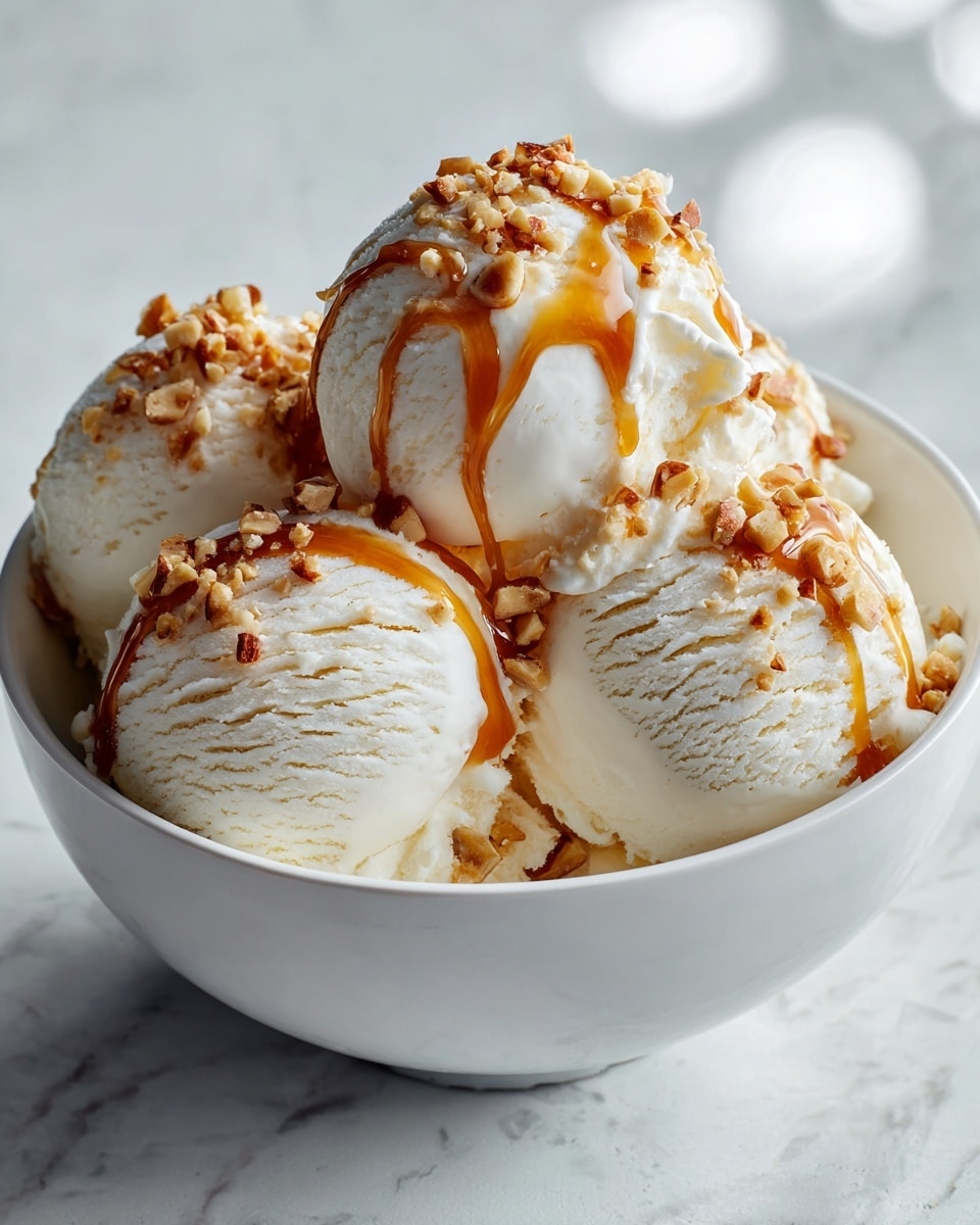 A white bowl filled with four round scoops of creamy vanilla ice cream, each scoop topped with a drizzle of caramel sauce that shines under soft light, with small bits of crushed nuts sprinkled on top and slightly embedded in the ice cream. The bowl sits on a white marbled surface with subtle reflections, highlighting the smooth and slightly textured ice cream. photo taken with an iphone --ar 4:5 --v 7