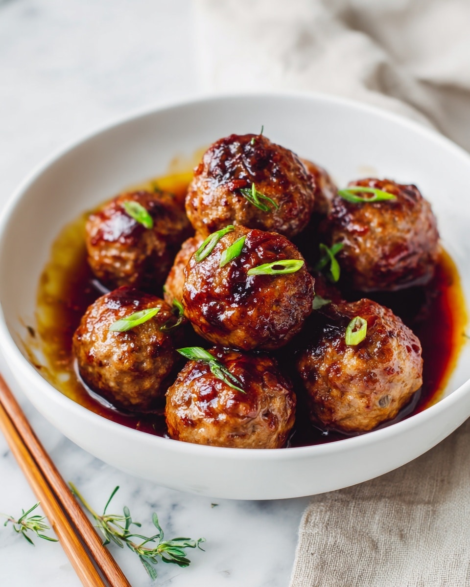 A white bowl filled with ten shiny, golden-brown meatballs coated in a thick, glossy brown sauce. The meatballs are arranged in a slightly loose cluster, with small pieces of vibrant green chopped scallions scattered evenly on top. The bowl sits on a white marbled surface with a pair of light wooden chopsticks leaning beside it. A few green herbs are slightly visible on the side, adding a touch of fresh color to the scene. photo taken with an iphone --ar 4:5 --v 7