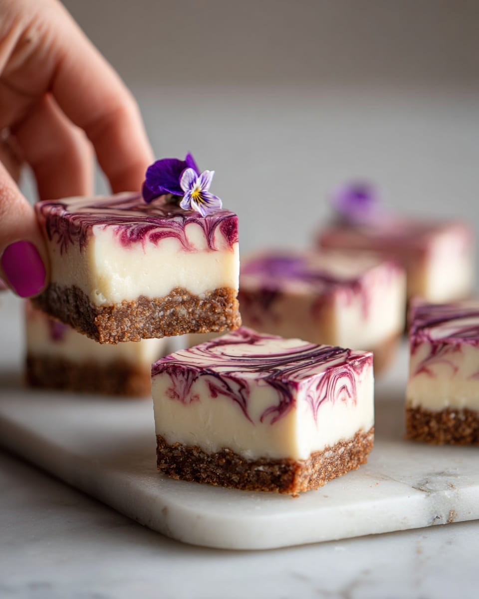 Four round balls sit on a white plate placed on a white marbled surface; three are whole, and one is broken open showing a fluffy white inside. Each ball is covered in a bright pink outer layer that is thick and smooth and then a crust of tiny round sprinkles in pink, blue, yellow, and white covers the outside. The broken ball reveals the soft white inside which looks light and airy, creating a strong contrast with the colorful outer layers. Photo taken with an iphone --ar 4:5 --v 7