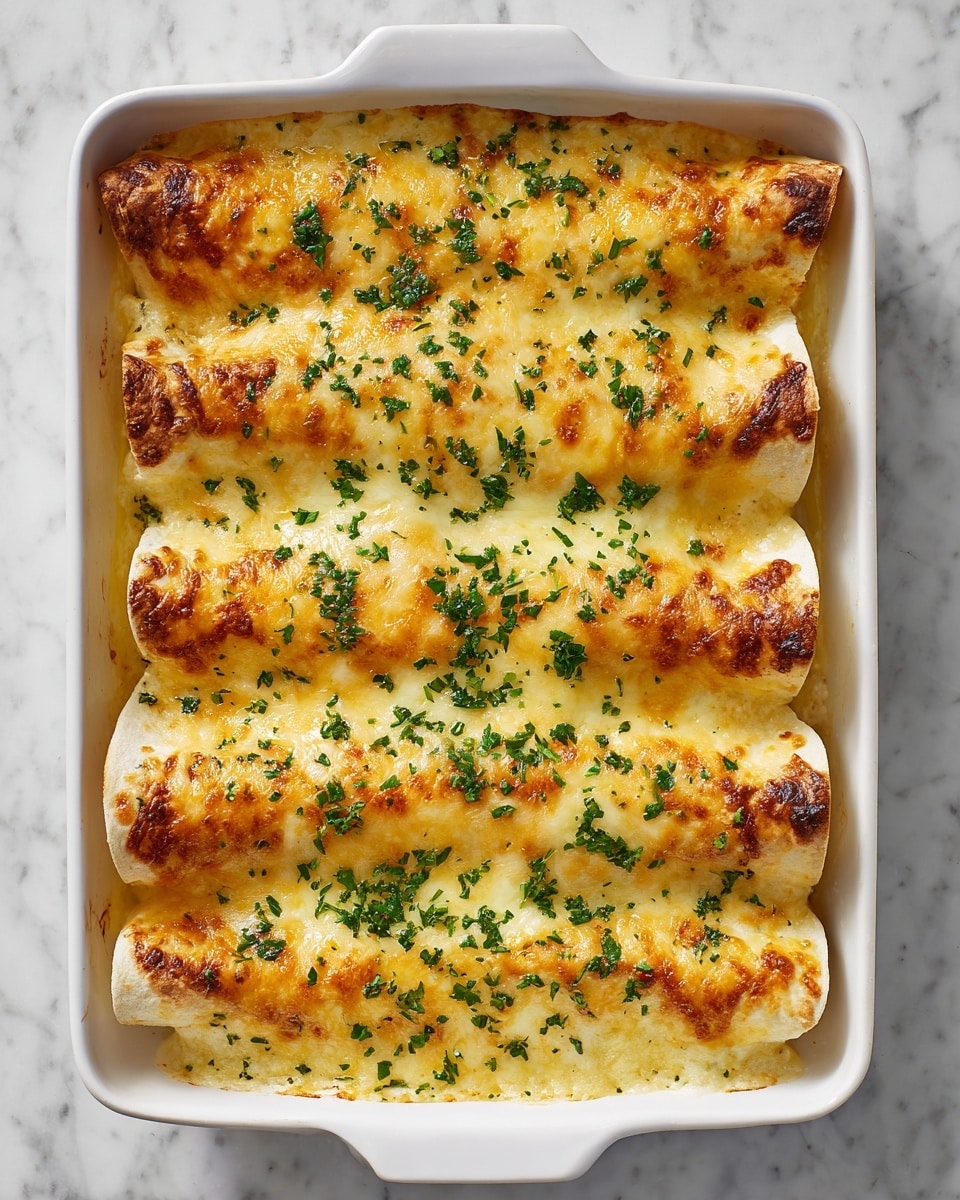 The image shows a white rectangular baking dish filled with eight rolled enchiladas placed side by side. The enchiladas are covered with a thick layer of golden melted cheese that appears bubbly and slightly browned in spots. A generous amount of finely chopped green herbs is sprinkled evenly on top, adding a fresh contrast to the warm cheese layer. The edges of the white sauce or filling slightly peek out between the tortillas, giving a creamy texture visible beneath the cheese. The surface beneath the dish has a white marbled texture. photo taken with an iphone --ar 4:5 --v 7