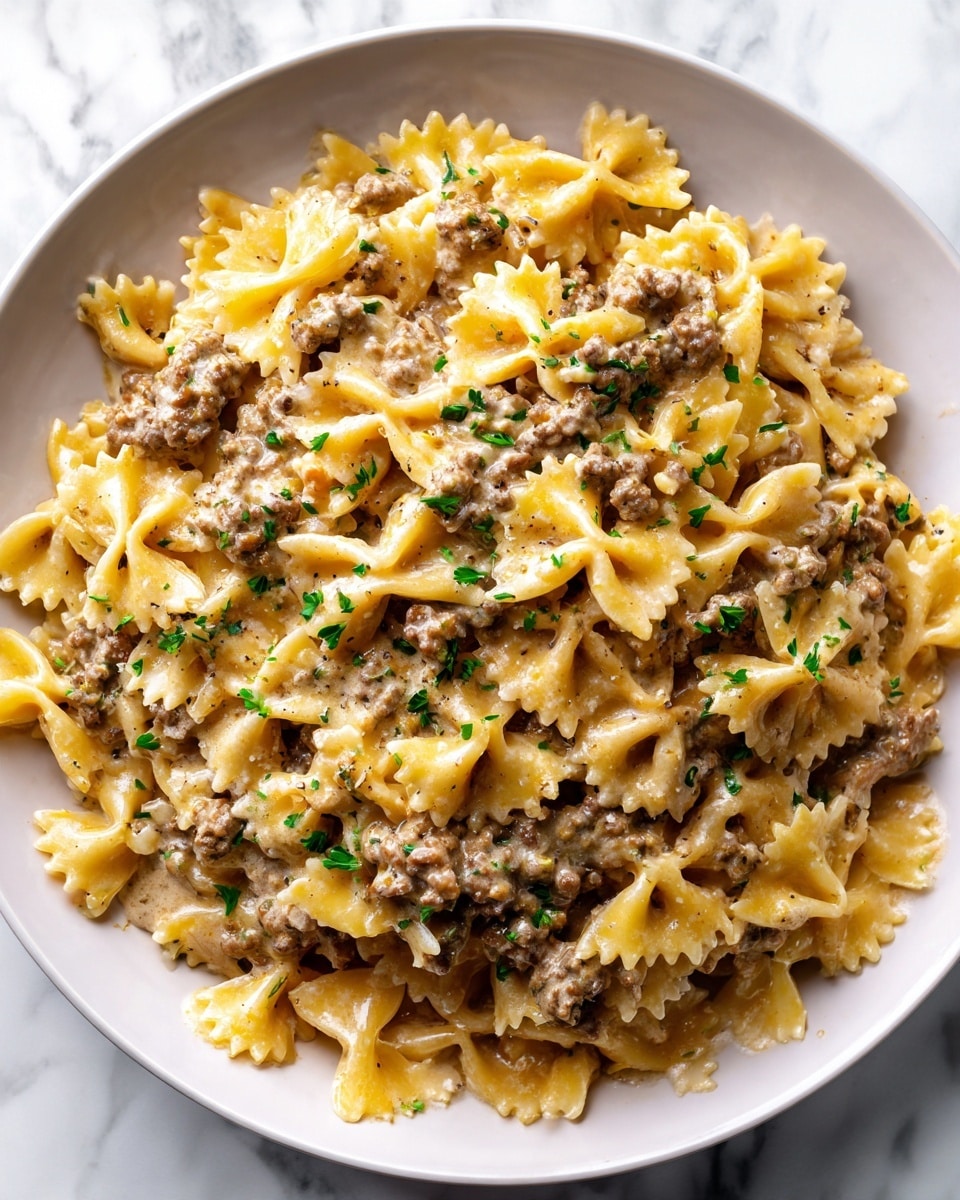 A white plate filled with farfalle pasta covered in a light brown meat sauce, with small bits of ground meat spread evenly over the pasta. The farfalle pasta is a soft yellow color with a slightly curved, bow-tie shape, and the sauce has a smooth, slightly chunky texture. Tiny green herb pieces are sprinkled on top, adding a touch of color contrast. The plate is set on a white marbled surface. photo taken with an iphone --ar 4:5 --v 7