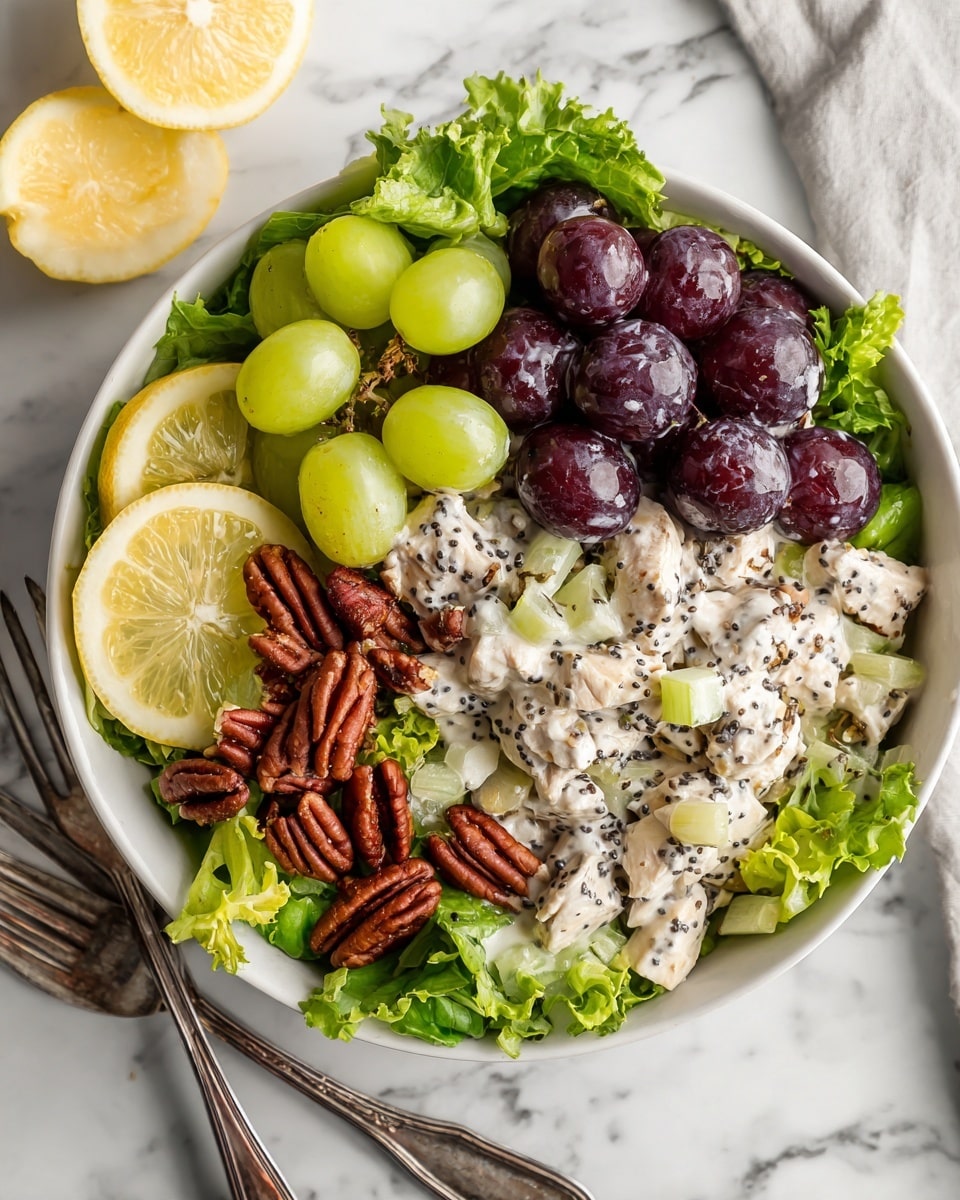 A white bowl filled with a layered chicken salad sits on a white marbled surface. The bottom layer is fresh, bright green leafy lettuce spread evenly inside the bowl. On top of the lettuce, there is a creamy mixture of white chicken pieces mixed with light green celery slices, deep red grape halves, and small brown pecan nuts scattered throughout. The salad is lightly sprinkled with tiny black poppy seeds and topped with fresh green parsley leaves. Two silver forks rest on the left side inside the bowl, and two lemon slices lay on the right edge of the bowl. Photo taken with an iphone --ar 4:5 --v 7